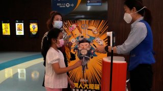 Visitors to a cinema showing the latest "Minions: The Rise of Gru" movie get their tickets checked in Beijing