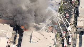 Firefighters on ladder trucks spray water on a fire in Boyle Heights Monday Sept. 5, 2022.