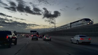 A Metrolink train passes early morning commuters along Interstate 5 in Los Angeles on Oct. 4, 2018.