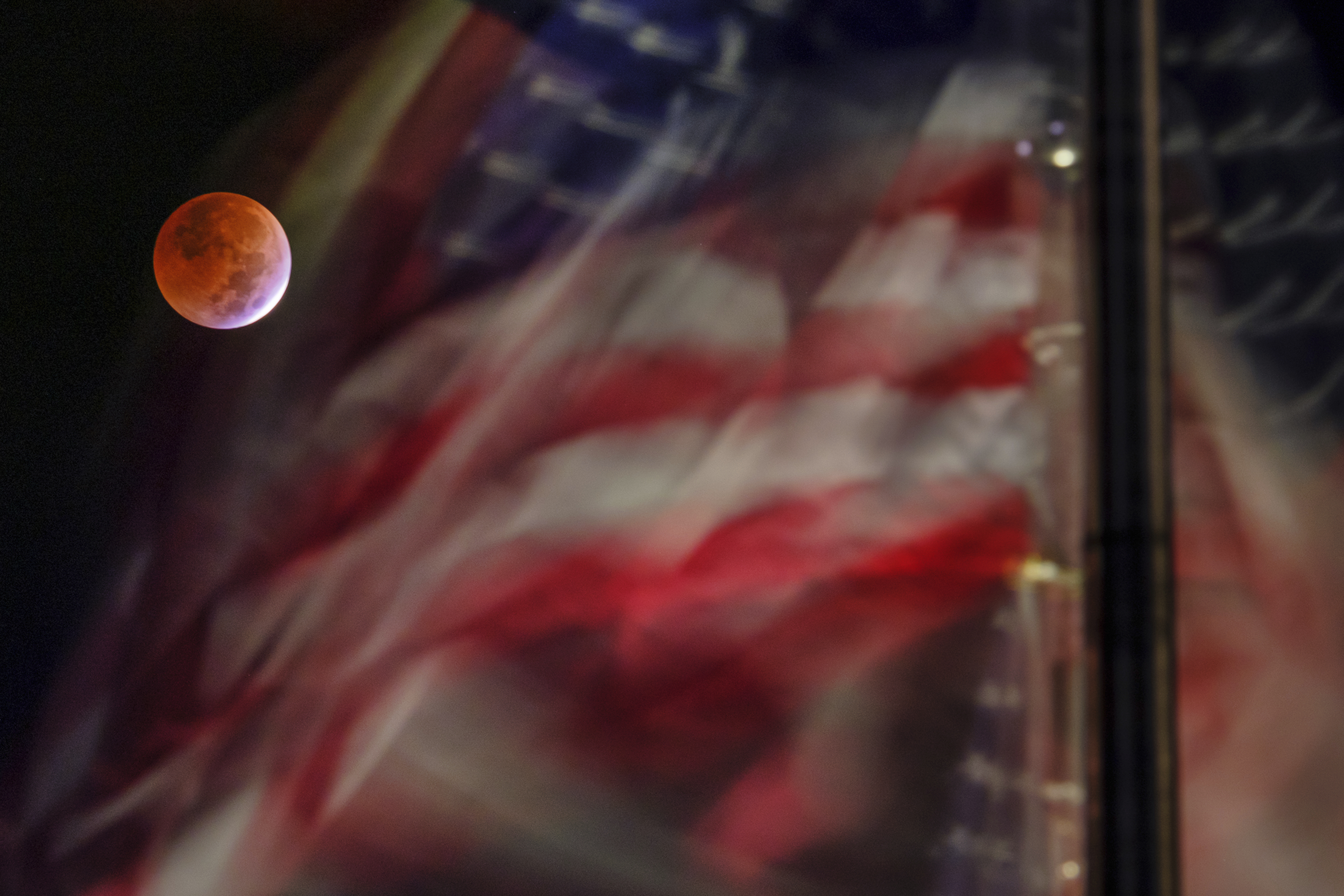 The lunar eclipse is framed by the U.S. flag on the National Mall in Washington, D.C., Nov. 8, 2022. Early morning voters might have seen the blood moon on Election Day – the last blood moon for the next three years.