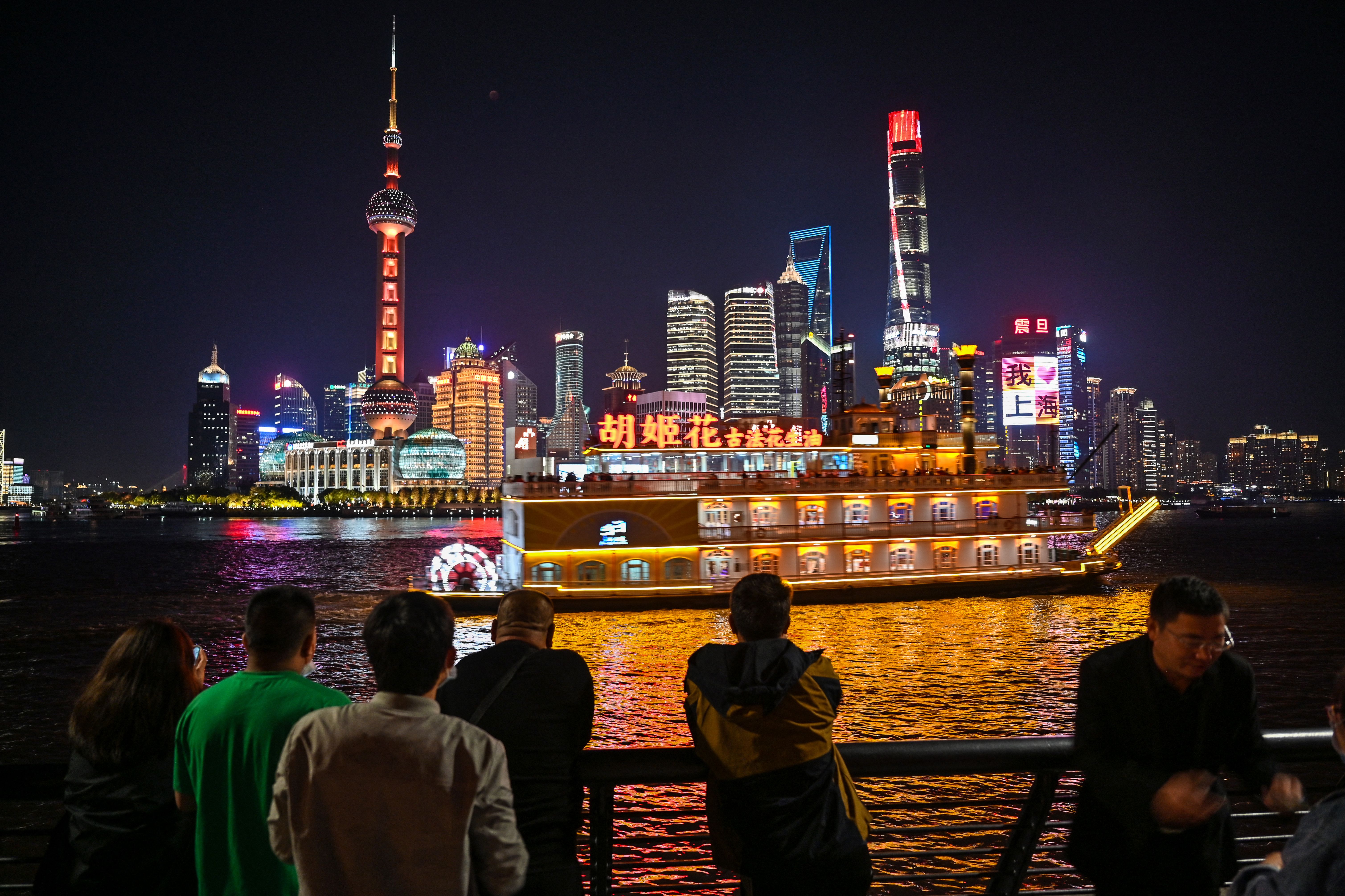 People watch the total lunar eclipse in progress from the Bund promenade along the Huangpu River in Shanghai, Nov. 8, 2022.