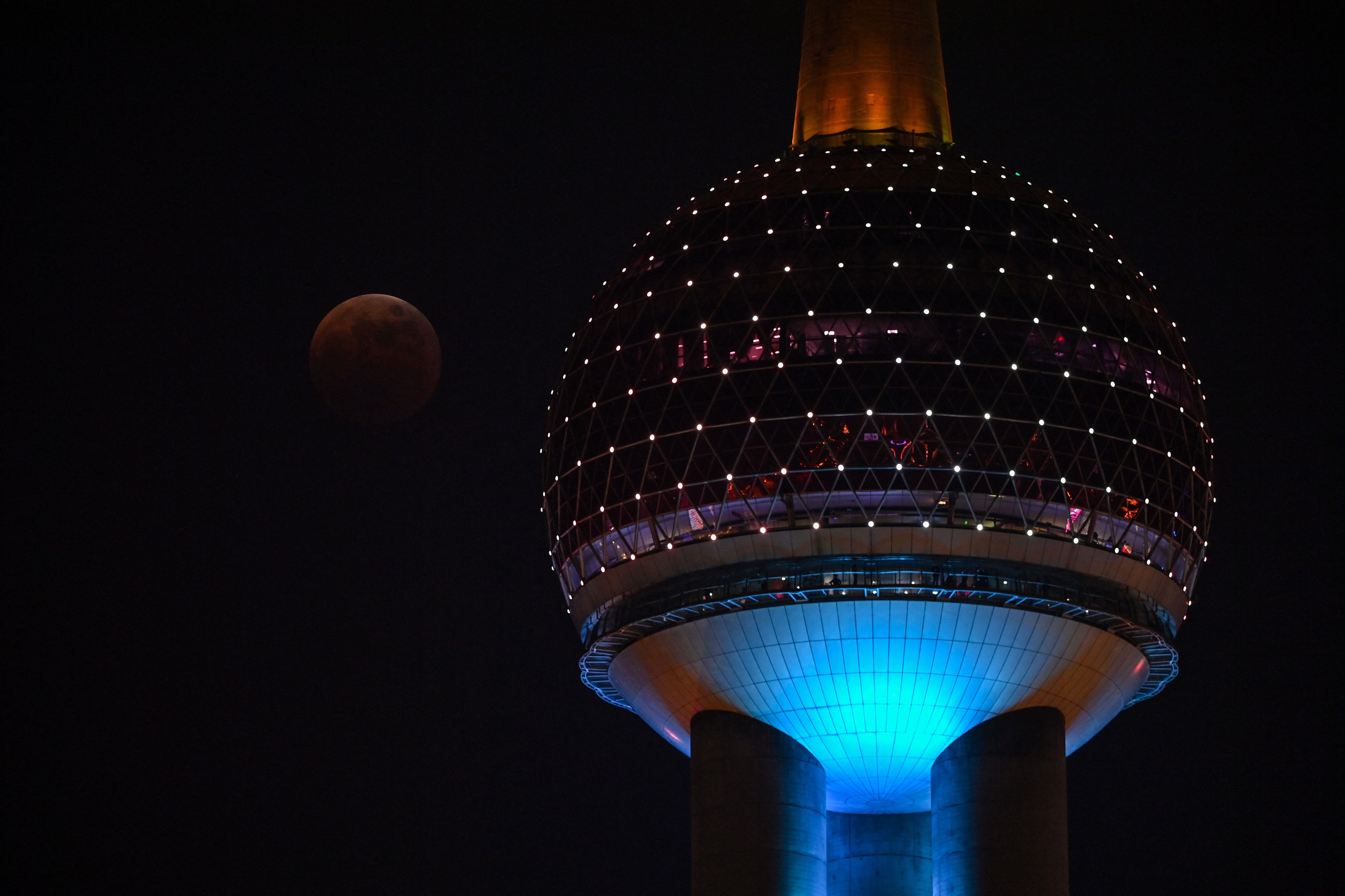 People watch the total lunar eclipse in progress from the Bund promenade along the Huangpu River in Shanghai, Nov. 8, 2022.