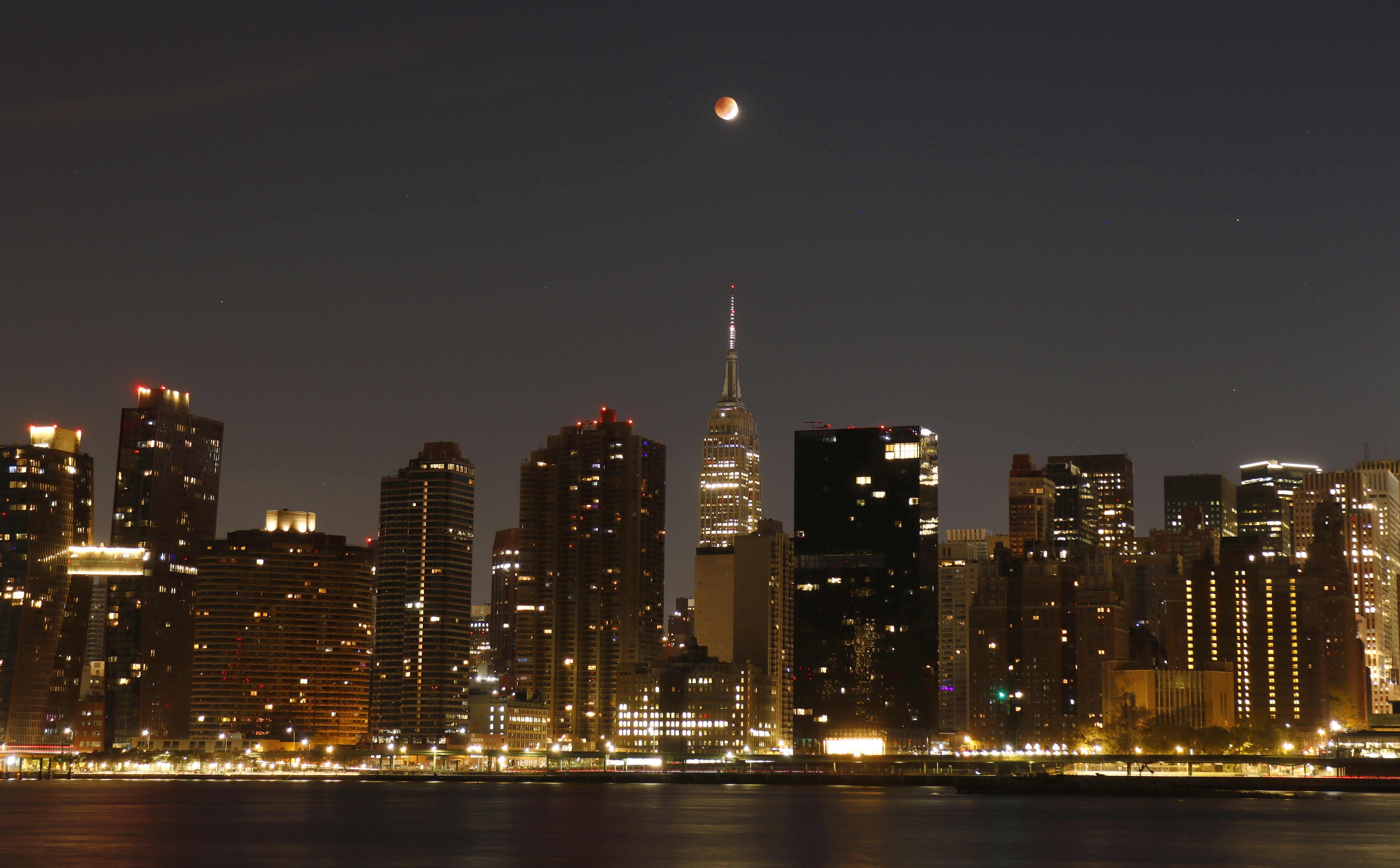 The blood-red full Beaver Moon passes over the Empire State Building during a total lunar eclipse on Nov. 8, 2022, in New York City.