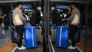 Passengers wait to board a train at Hongqiao railway station in Shanghai on December 6, 2022.