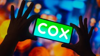 In this photo illustration, the Cox Communications logo is displayed on a smartphone screen.