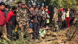 Locals watch the wreckage of a passenger plane in Pokhara, Nepal, Sunday, Jan.15, 2023.