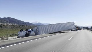 A big rig on its side on the 15 Freeway.