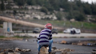 FILE – A masked Palestinian sits during a support rally for the Palestinian prisoners, outside Ofer, an Israeli military prison near the West Bank city of Ramallah, Friday, March 1, 2013.