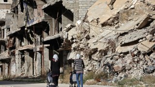 Residents of the Palestinian Yarmuk camp, on the southern outskirts of the Syrian capital Damascus, walk past destroyed buildings on November 25, 2020.