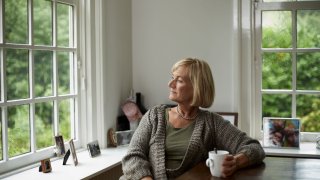 An older woman having a cup of coffee.