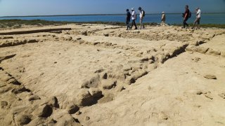 Archaeologists and journalists walk past uncovered ruins on Siniyah Island in Umm al-Quwain, United Arab Emirates, March 20, 2023. Archaeologists said they have found the oldest pearling town in the Persian Gulf on an island off one of the northern sheikhdoms of the United Arab Emirates.