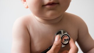 Doctor listening to chest of baby boy with stethoscope