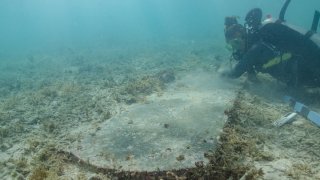 This image courtesy of the National Park Service shows University of Miami graduate student Devon Fogarty examining the headstone of John Greer, which was found underwater by archeologists during a survey at Dry Tortugas National Park in August 2022, in Florida.