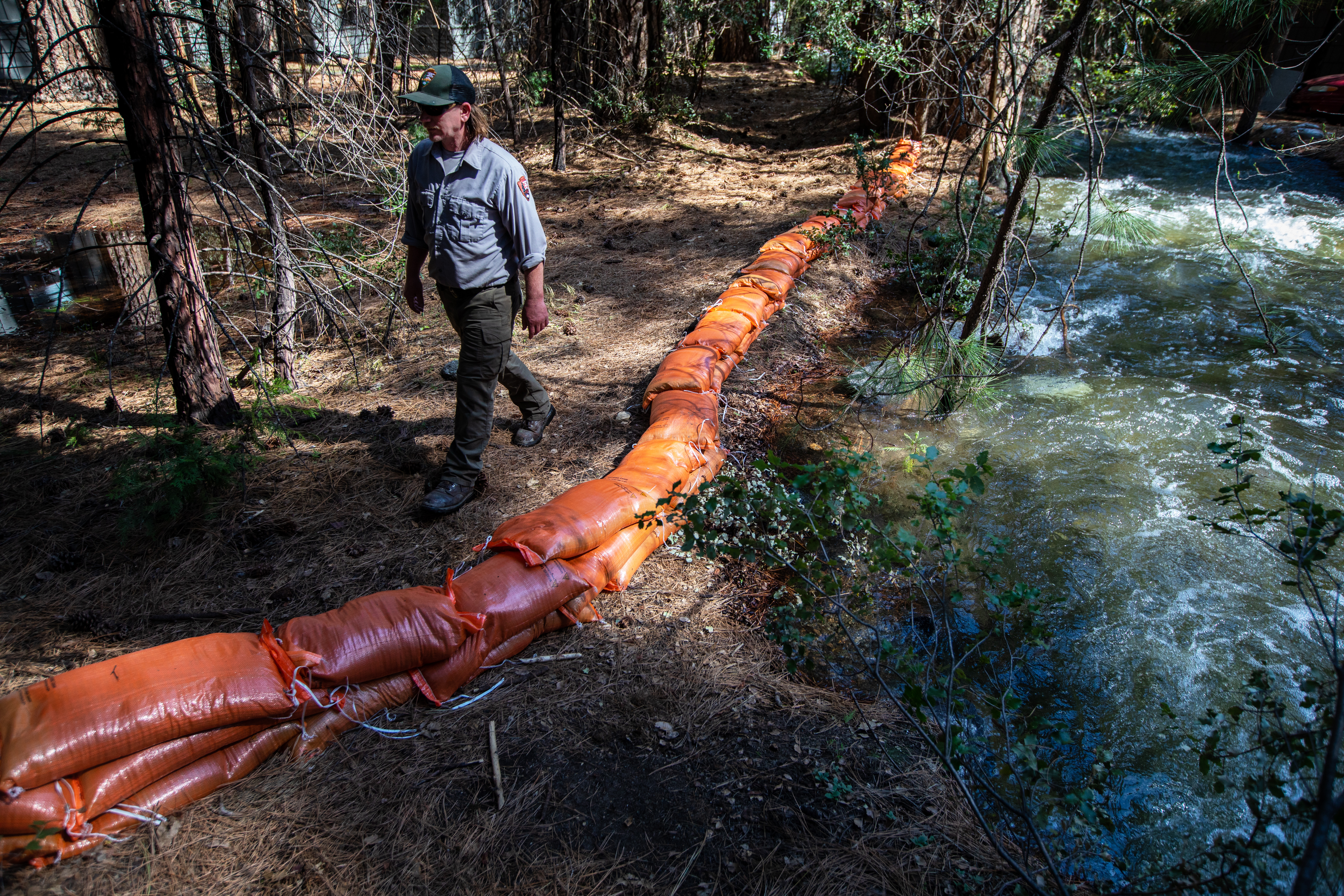 Brendan Ward with the Valley Buildings, and Groundwater Department checks the Indian Canyon Creek water level and sandbags next to staff housing below the medical clinic on Thursday, April 27, 2023, inside Yosemite National Park.