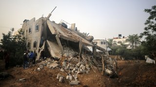 Palestinians gather near a destroyed building following an Israeli air strike in Deir el-Balah, central Gaza Strip.