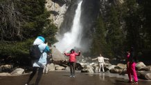 People take photos as water flows forcefully down Lower Yosemite Fall in Yosemite Valley on April 28, 2023 in Yosemite National Park, California.