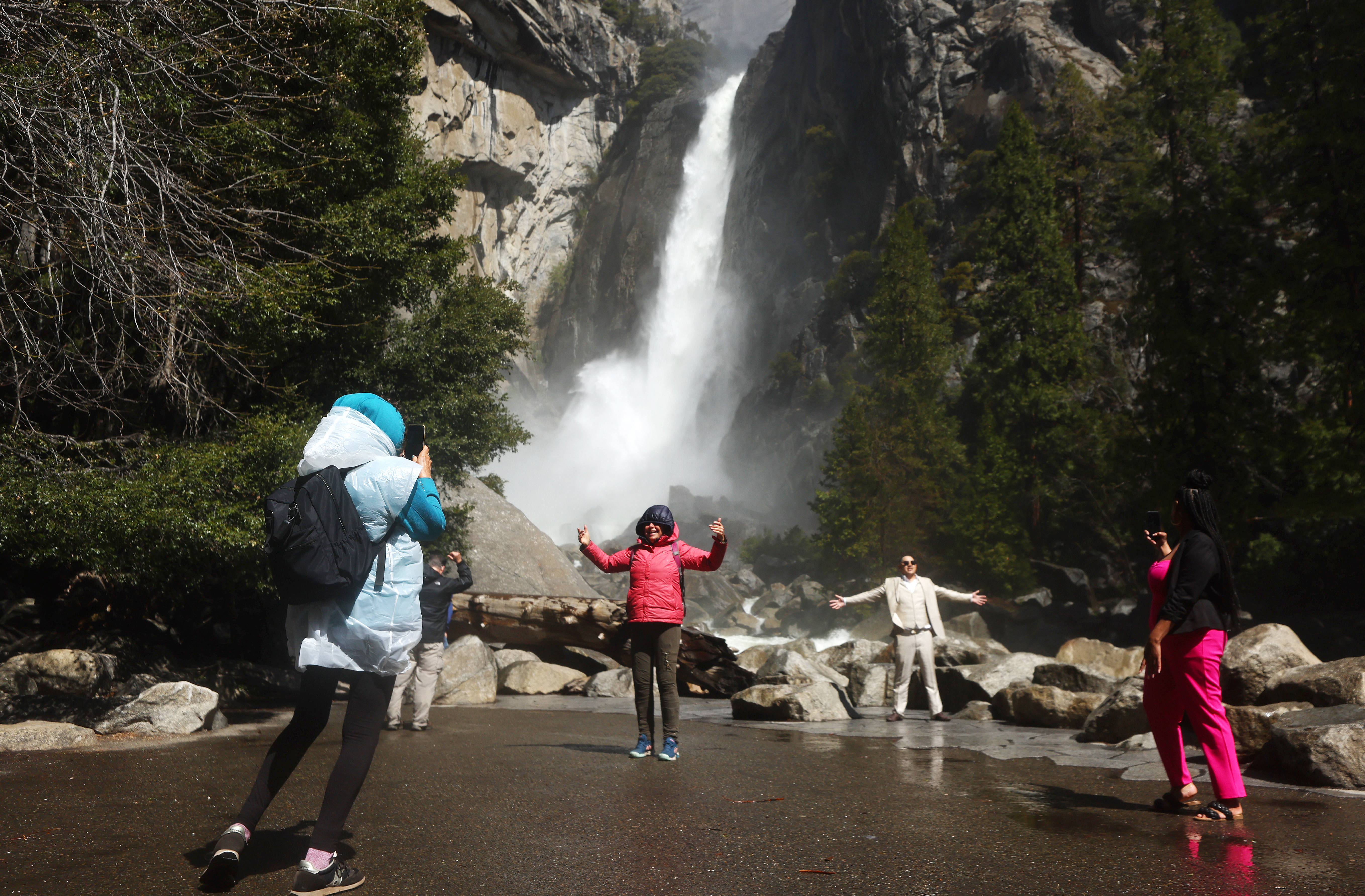 People take photos as water flows forcefully down Lower Yosemite Fall in Yosemite Valley on April 28, 2023 in Yosemite National Park, California. 
