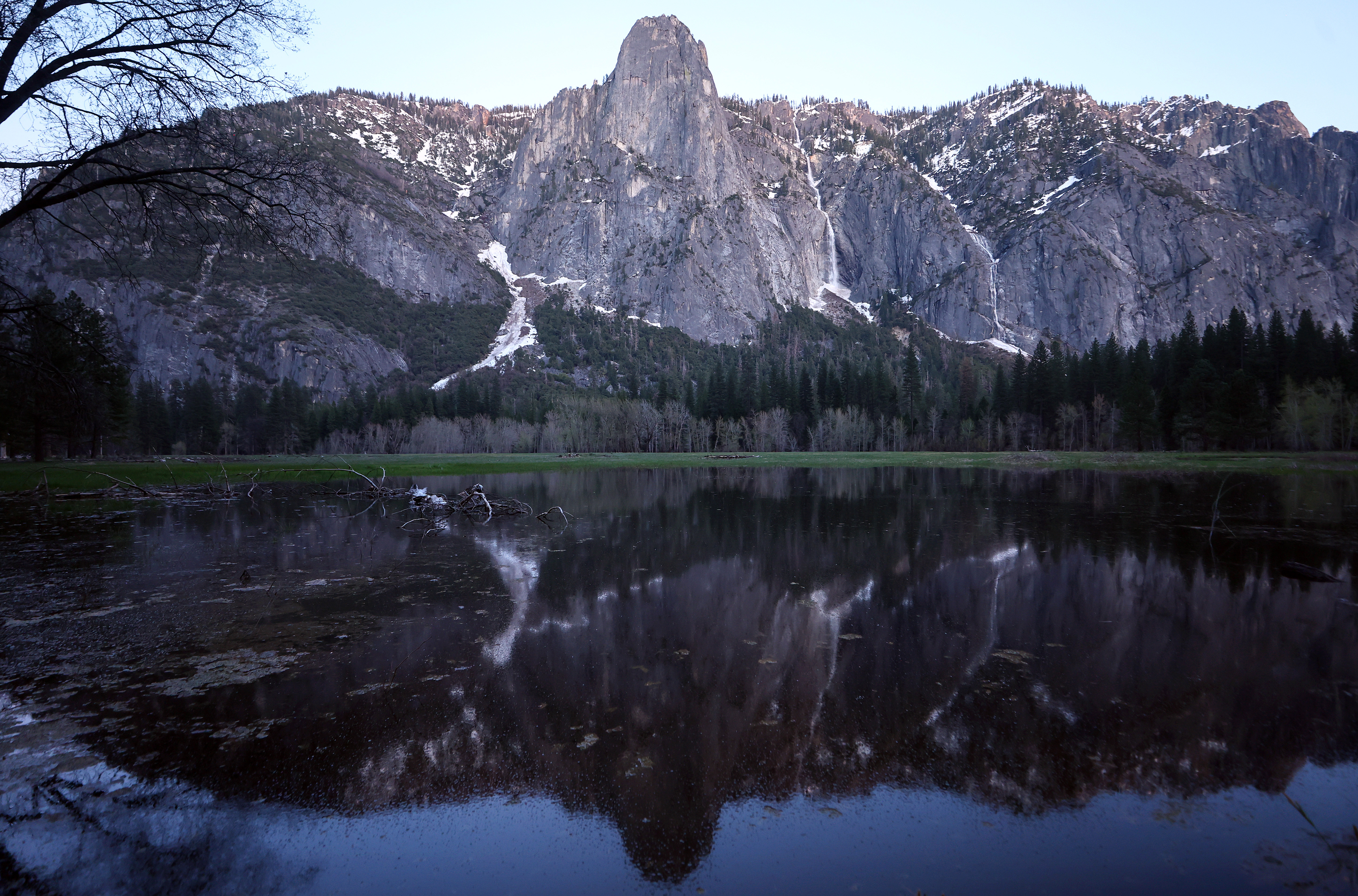 A meadow begins to flood in Yosemite Valley, with a waterfall  flowing near snow on April 28, 2023 in Yosemite National Park, California. 