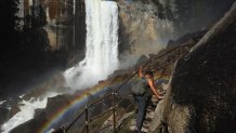 A person climbs a stairway leading to the top of Vernal Fall, with a rainbow visible, as warming temperatures have increased snowpack runoff, on April 28, 2023 in Yosemite National Park, California.