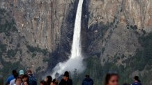 Visitors gather at an overlook as water flows forcefully down Bridalveil Fall.