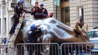 NYPD Emergency Service Unit officers negotiate with a man who climbed the Charging Bull sculpture in the Financial District, Manhattan, New York City on Sunday, April 16, 2023.