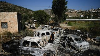 A Palestinian man inspects scorched cars, including some junked for spare parts, in the West Bank village of A Laban al-Sharkiyeh, Wednesday, June 21, 2023. Israeli settlers set fire to cars after four Israelis were killed by Palestinian gunmen in the northern West Bank on Tuesday. (AP Photo/Majdi Mohammed)