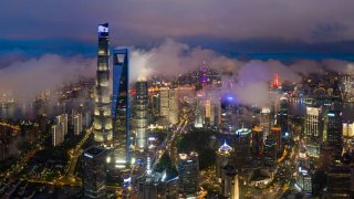 Aerial view of illuminated skyscrapers standing at the Pudong Lujiazui Financial District at night on June 10, 2022 in Shanghai, China.