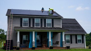 Brian Hoeppner, left, and Nicholas Hartnett, owner of Pure Power Solar, install a solar panel on the roof of a home