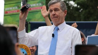 FILE – North Carolina Democratic Gov. Roy Cooper affixes his veto stamp to a bill banning nearly all abortions after 12 weeks of pregnancy at a public rally, May 13, 2023, in Raleigh, N.C. Transgender rights take center stage in North Carolina again Wednesday, Aug. 16, as GOP supermajorities in the General Assembly attempt to override the governor’s vetoes of legislation banning gender-affirming health care for minors and limiting transgender participation in school sports.