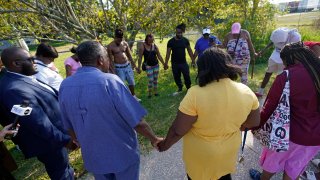 Residents gather for a prayer near the scene of a mass shooting at a Dollar General store, Saturday, Aug. 26, 2023, in Jacksonville, Fla. (AP Photo/John Raoux)