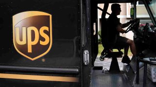 FILE - United Parcel Service driver Hudson de Almeida steers through a neighborhood while delivering packages, June 30, 2023, in Haverhill, Mass.