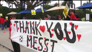 Workers hold up a sign that reads, "Thank you Messi."