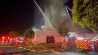 Firefighters worked through the morning Thursday to protect nearby businesses from a fire at a commercial building in Santa Ana.