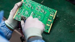 A worker holds a circuit board.