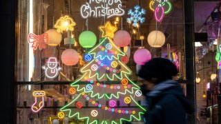 A person walks past a Christmas lighting display in a window at Bulbs NYC lighting store near Union Square in New York City, Dec. 20, 2022.