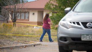 FILE - An onlooker walks along the police line outside Return to Nature Funeral Home facility in Penrose, Colo.