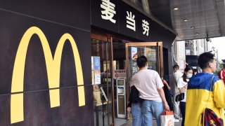 FILE - Customers wait for their takeout food outside a McDonald’s restaurant on May 1, 2022 in Beijing, China.