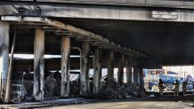 Los Angeles firefighters mop up from a fire under Interstate 10