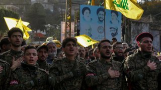 Pro-Iranian Hezbollah militants chant slogans as they walk in the beginning of the funeral procession of the party top commander Wissam tawil in the southern Lebanese village of Khirbit Selem.