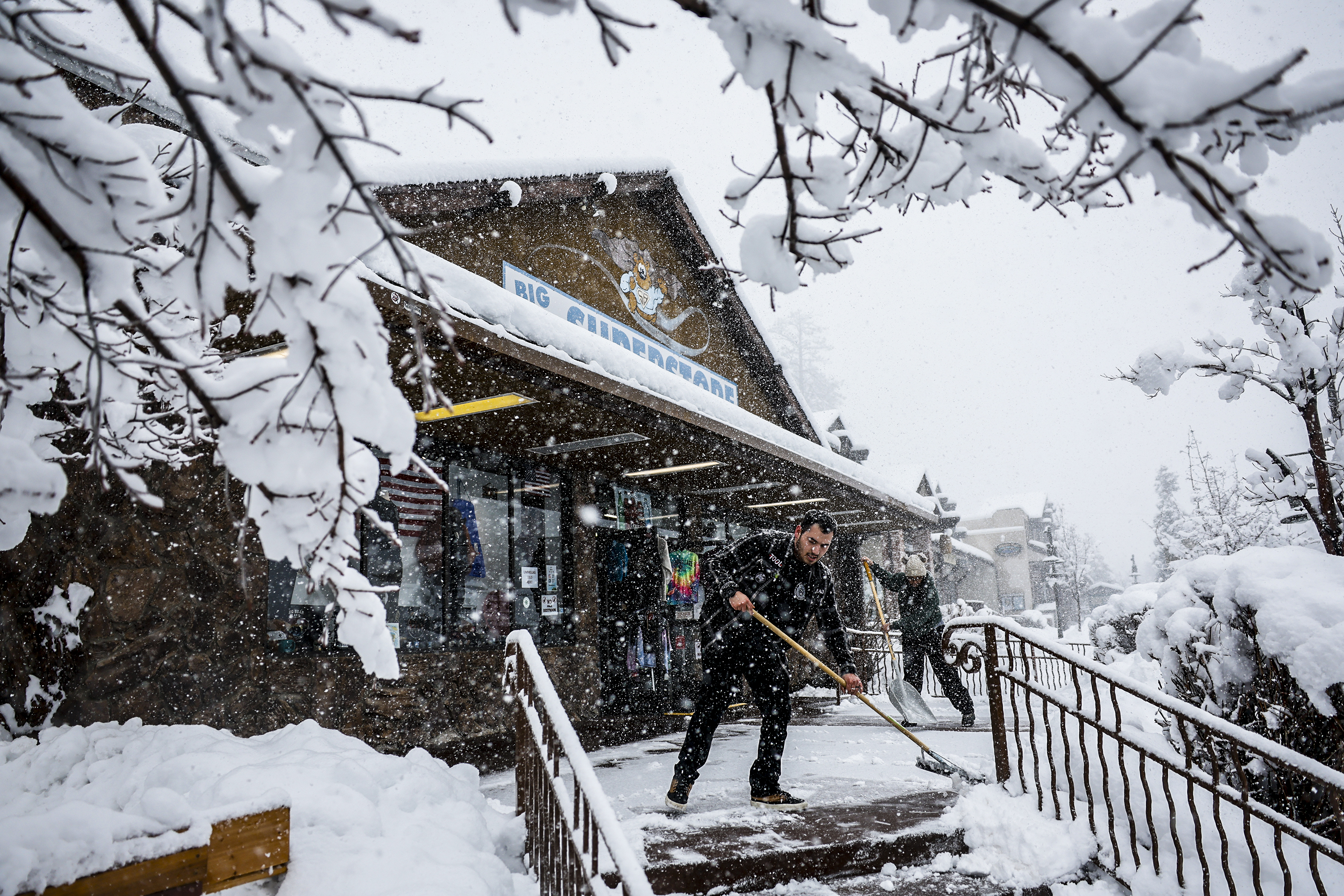 Big Bear, CA, Tuesday, February 6, 2024 – Brayan Arreola (cq) and Cynthia Ramirez clear snow from the porch of Big Bear Superstore as a snowstorm blankets  Big Bear. (Robert Gauthier/Los Angeles Times via Getty Images)