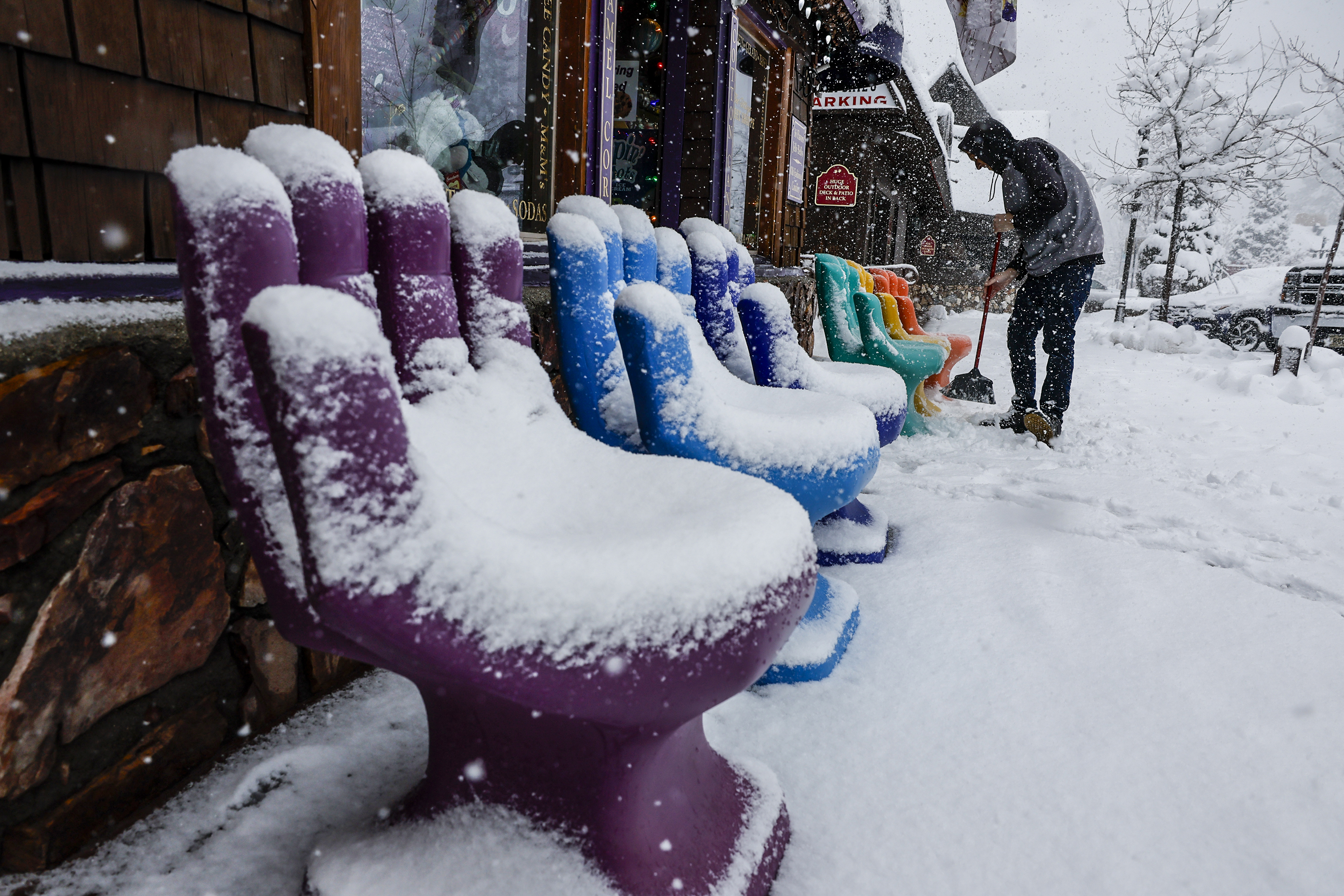 Big Bear, CA, Tuesday, February 6, 2024 – Tyler Reid tidies up the entrance to a candy shop in downtown as a snowstorm blankets Big Bear.  (Robert Gauthier/Los Angeles Times via Getty Images)