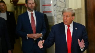 Former US President Donald Trump speaks to the media as his son Eric Trump looks on during the third day of his civil fraud trial in New York on October 4, 2023.