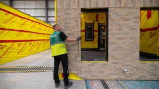 An employee checks the external casing with a spirit level in a modular house at the Tophat factory in Foston near Derby, UK, on Tuesday, Sept. 12, 2023.