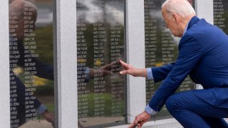 President Joe Biden reaches to touch the name of his uncle Ambrose J. Finnegan, Jr., on a wall.