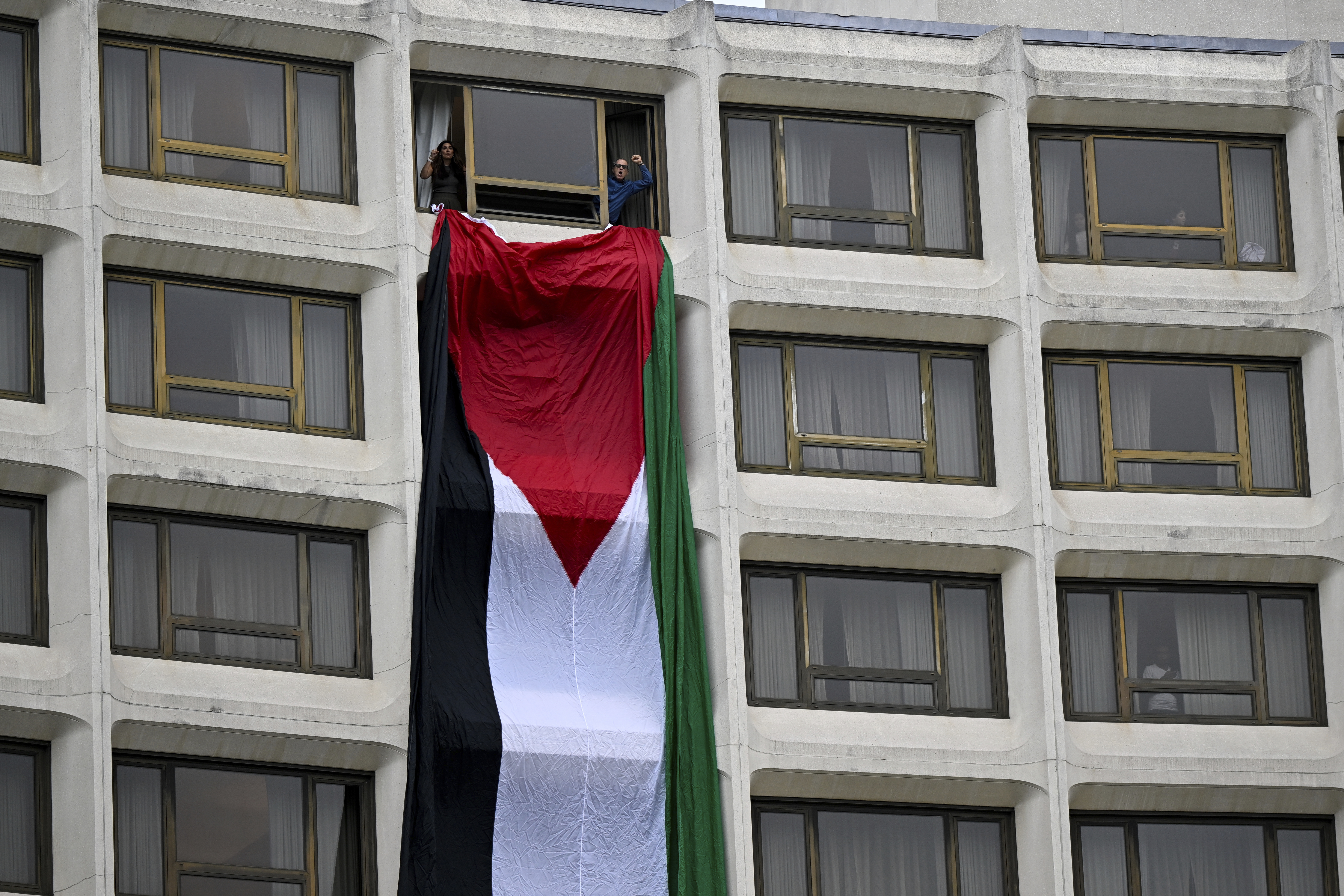 Demonstrators hang a Palestinian flag out a window at the Washington Hilton hotel during a protest over the Israel-Hamas war