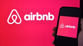 In this photo illustration, the Airbnb logo is displayed on a computer monitor and cell phone on February 13, 2024 in Los Angeles, California.