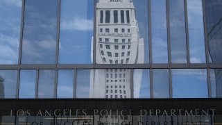 LA City Hall is seen in a reflection in the facade of LAPD headquarters.