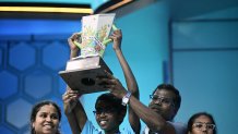Bruhat Soma (C), of St. Petersburg, Florida, celebrates with the trophy after winning the 96th Scripps National Spelling Bee