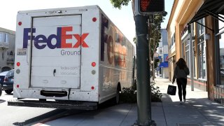 A pedestrian walks by a parked FedEx delivery truck on March 21, 2024 in San Francisco, California.