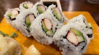 California Sushi Roll with crabmeat, avocado, cucumber and rice displayed on wooden serving tray.